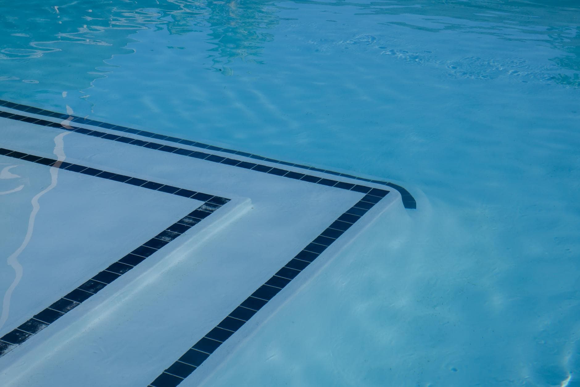 Serene view of a clear blue swimming pool with tiled steps and shimmering water.